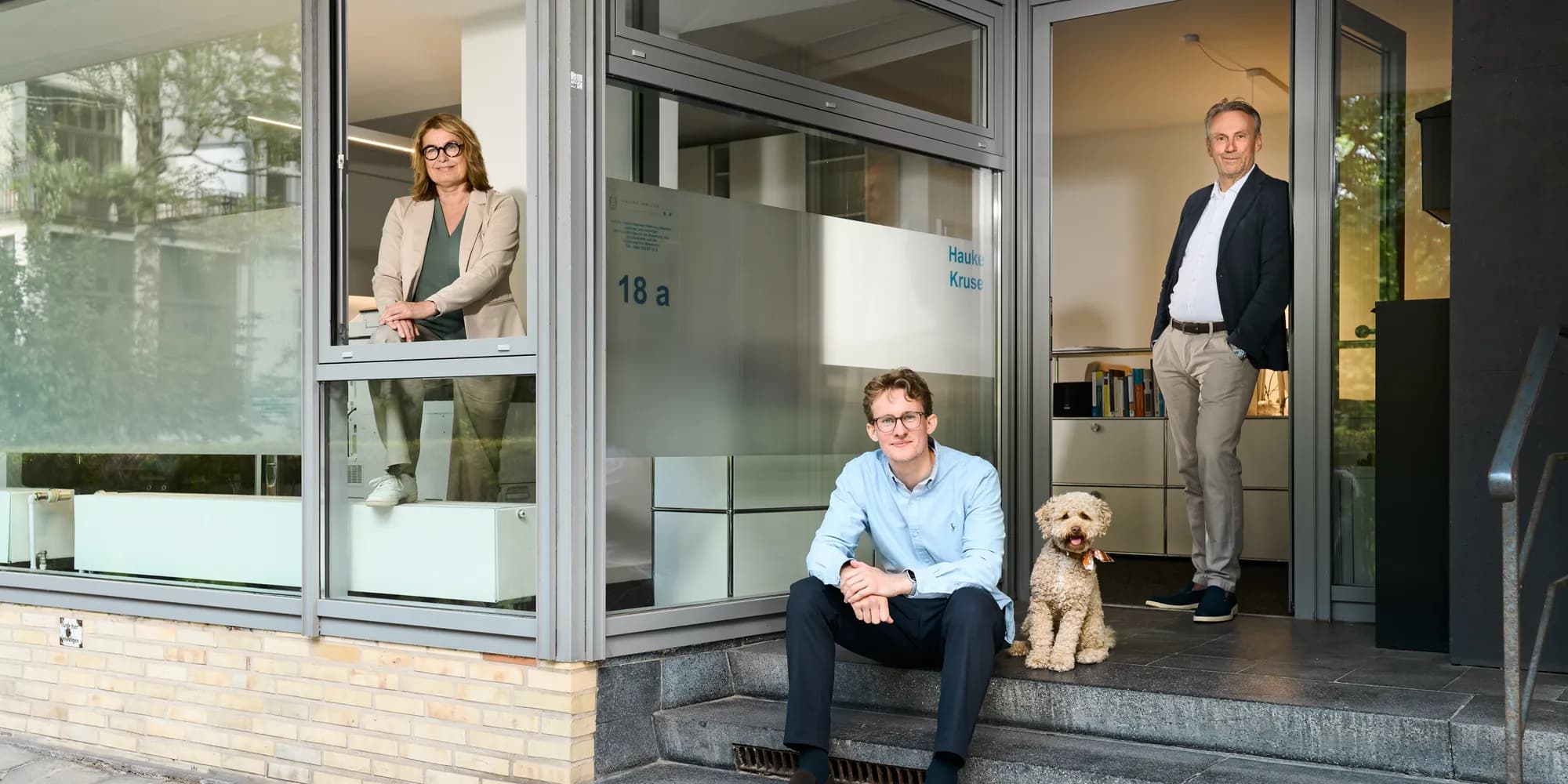 The team outside the Hamburg office: Susanne Schlicht at the window, Fabian Tiedemann with Sprotte on the steps, Hauke Kruse in the doorway